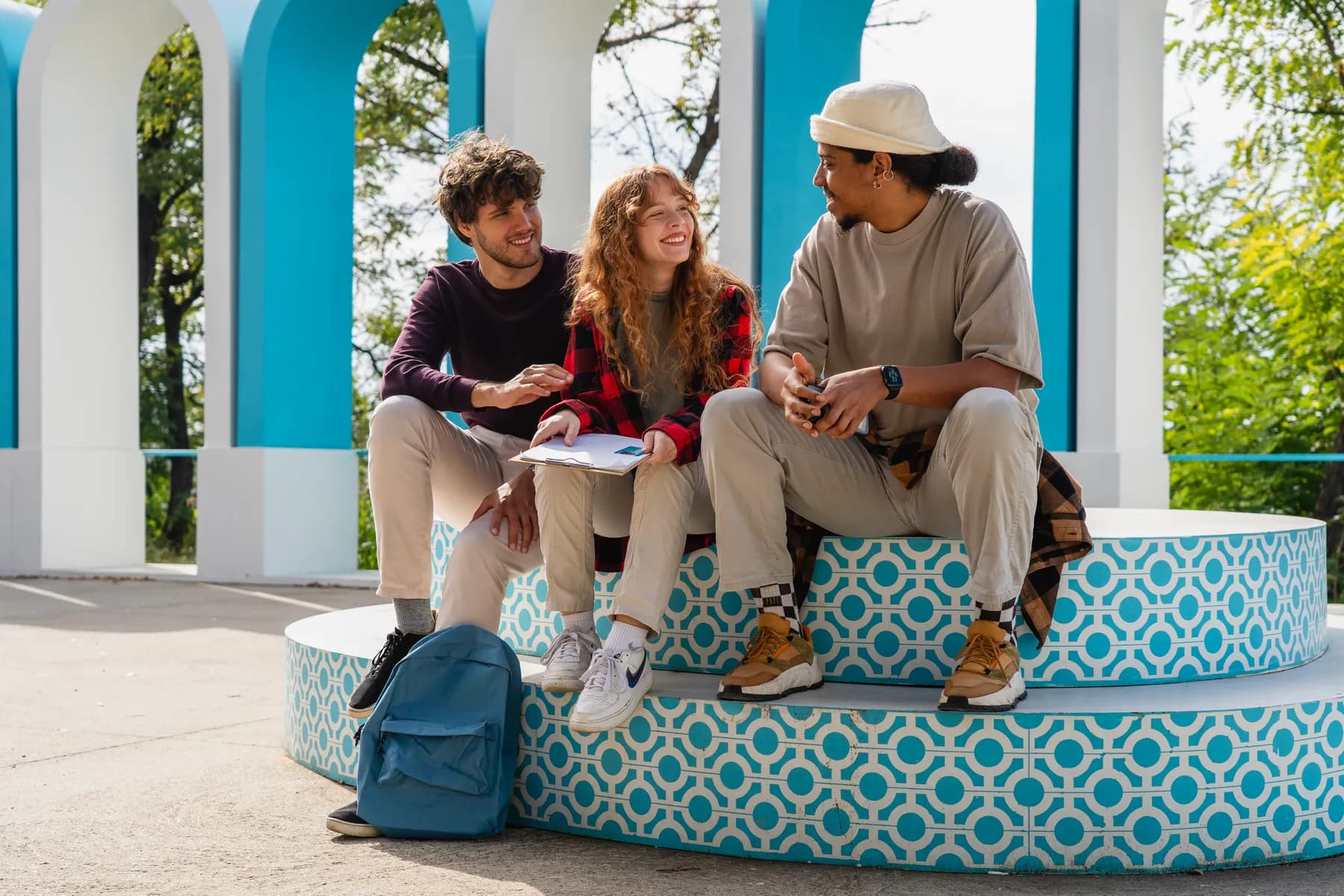 Three students chatting on a turquoise patterned bench